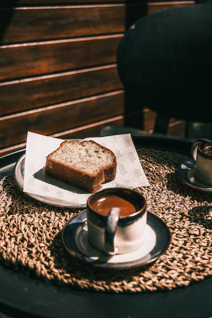 The Art of Drawing Readers In: Your attractive post title goes here A slice of banana bread with a cup of coffee on a sunlit table. Perfect for a cozy afternoon treat.