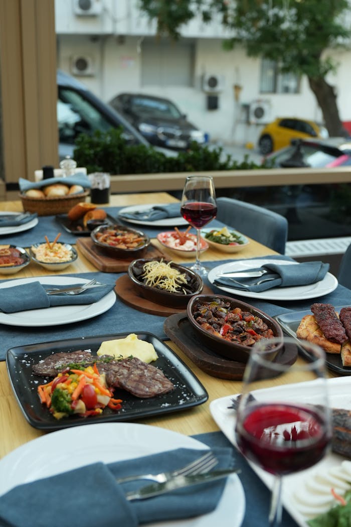 About A luxurious outdoor dining setup with an array of gourmet dishes and red wine, perfect for a social gathering.