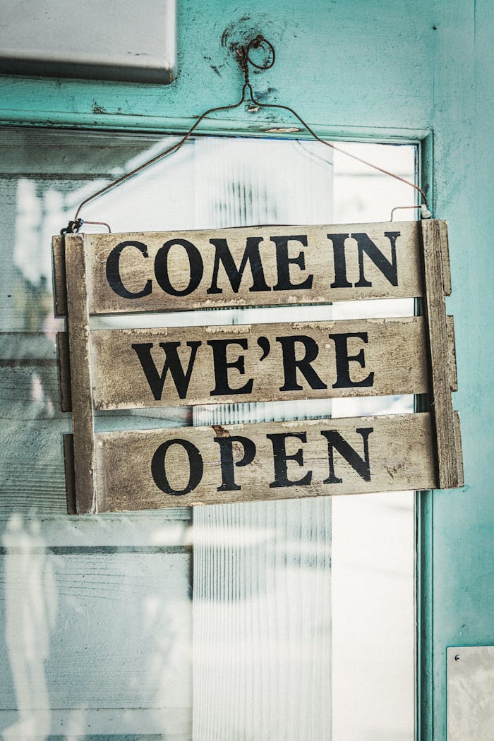 Mastering the First Impression: Your intriguing post title goes here Rustic wooden sign on a turquoise door reading 'Come In We're Open'.